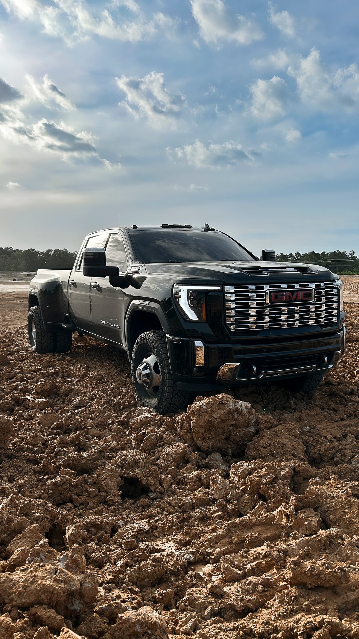 GMC Sierra lowrider truck shows show 2lowsierra Truck driving through a muddy field with a clear sky.