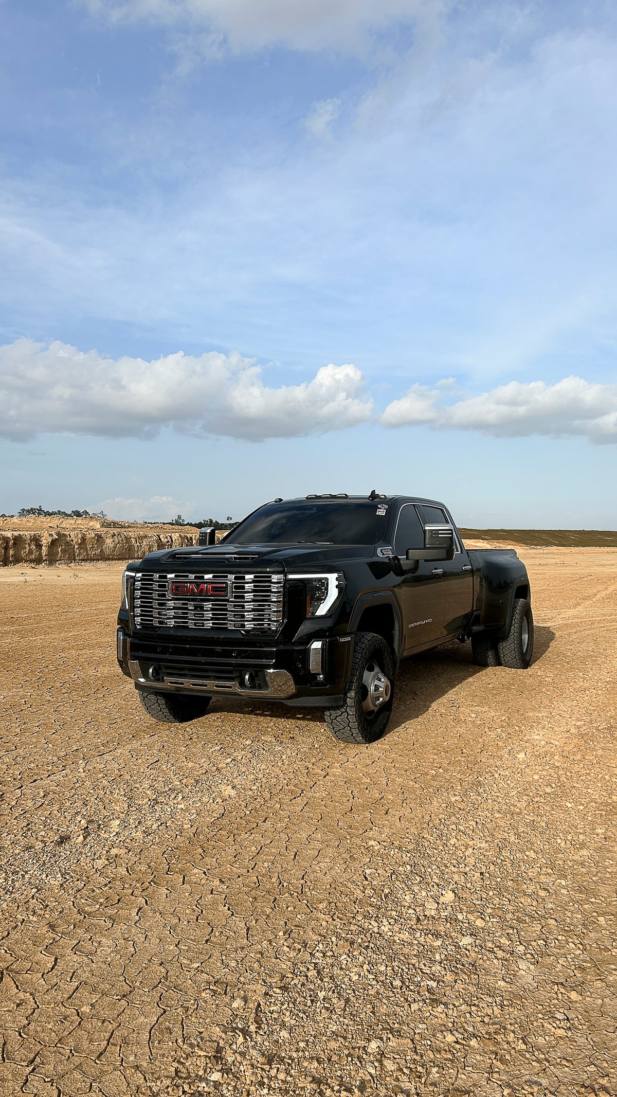 Black gmc 2lowsierra pickup truck on a dirt road with a clear sky