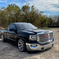 2lowsierra lowrider Black GMC truck GMC sierra Cadillac denali Escalade parked on a gravel surface with trees and blue sky in the background 