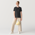 Woman wearing a black 2lowsierra 2LS t-shirt and beige pants with a yellow bag on a light gray background GMC Sierra Denali Cadillac Escalade